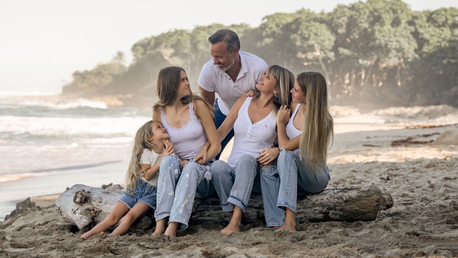 Family enjoying quality time together while sitting on coastal rocks at sunset on a beautiful beach.