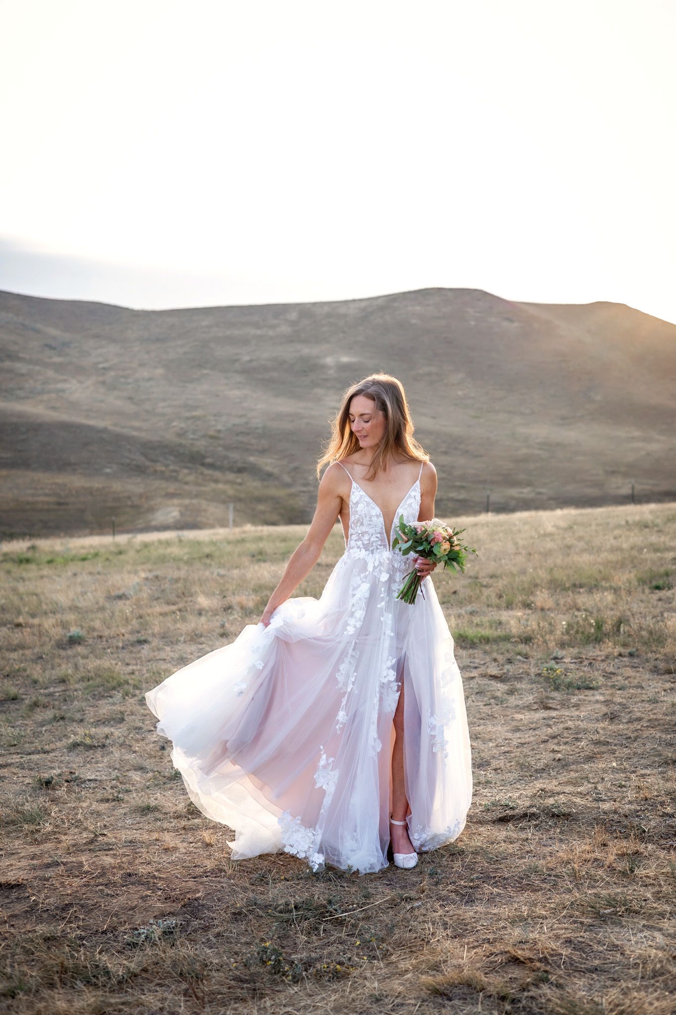 Elegant bride in white dress poses on deck with snowy forest backdrop.