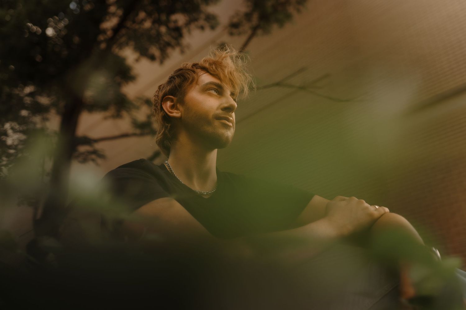Silhouette of a person in profile against a blurred green and brown natural background.