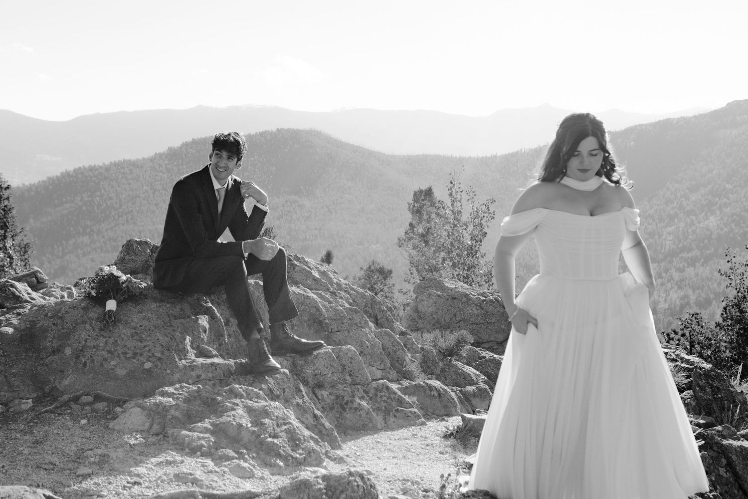 Wedding couple sharing romantic moment by vintage car on mountain road at dusk.