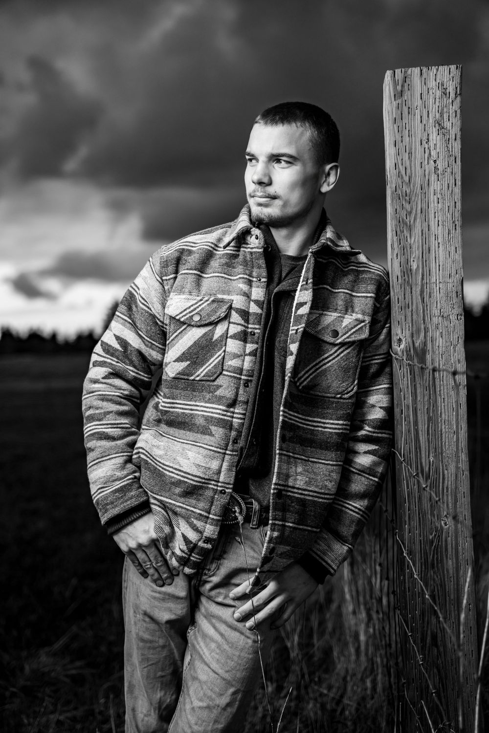 Black and white portrait series showing a person in a striped jacket leaning against a wooden post at dusk.