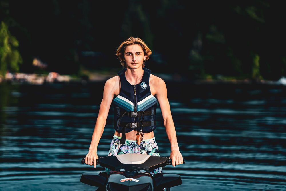 Action shot of jet ski rider creating wake spray on blue water.