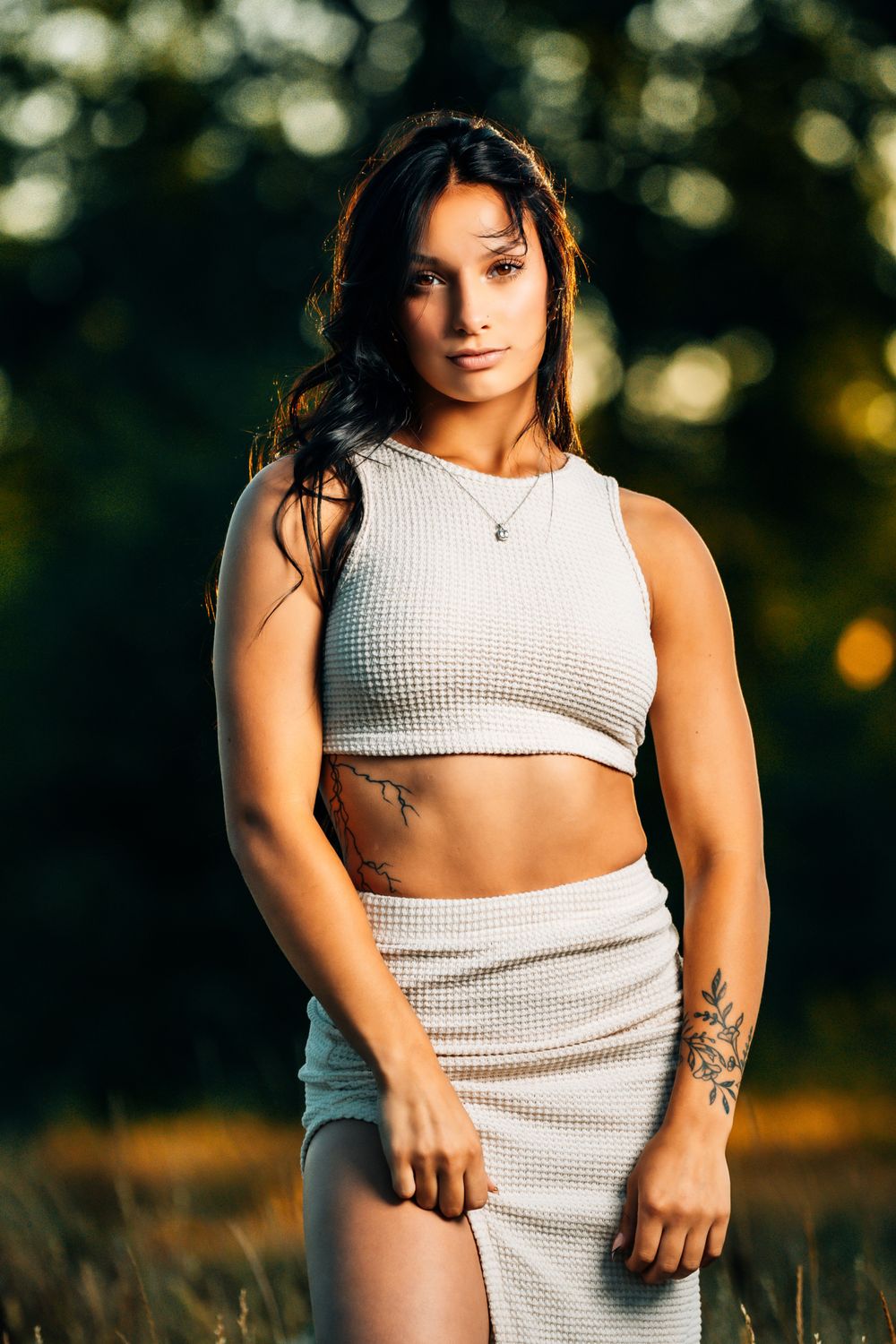 Sunset portrait of someone in a white ribbed crop top and skirt set in a natural setting.
