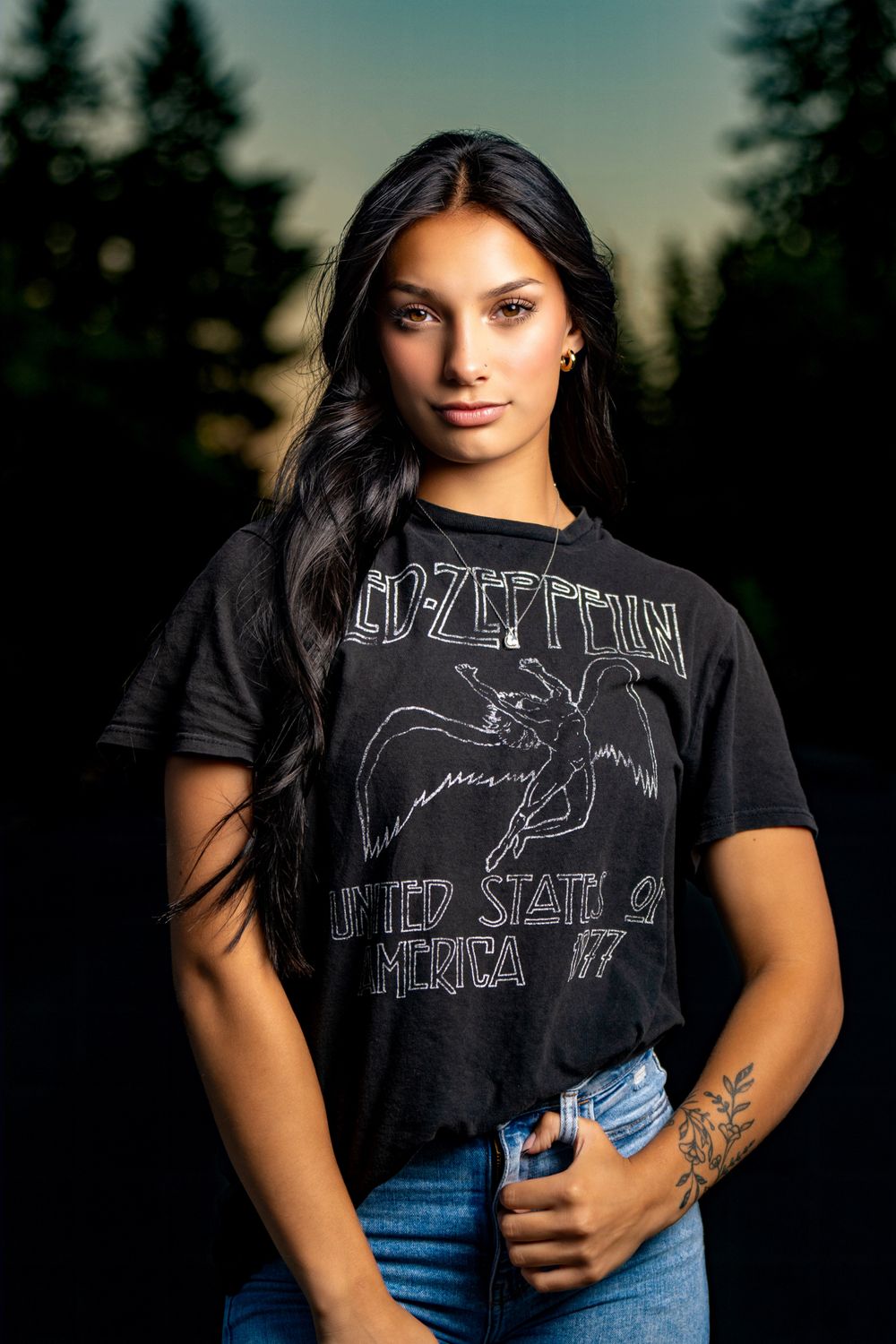 Dramatic portrait series in black band t-shirt and denim against forest backdrop at sunset.