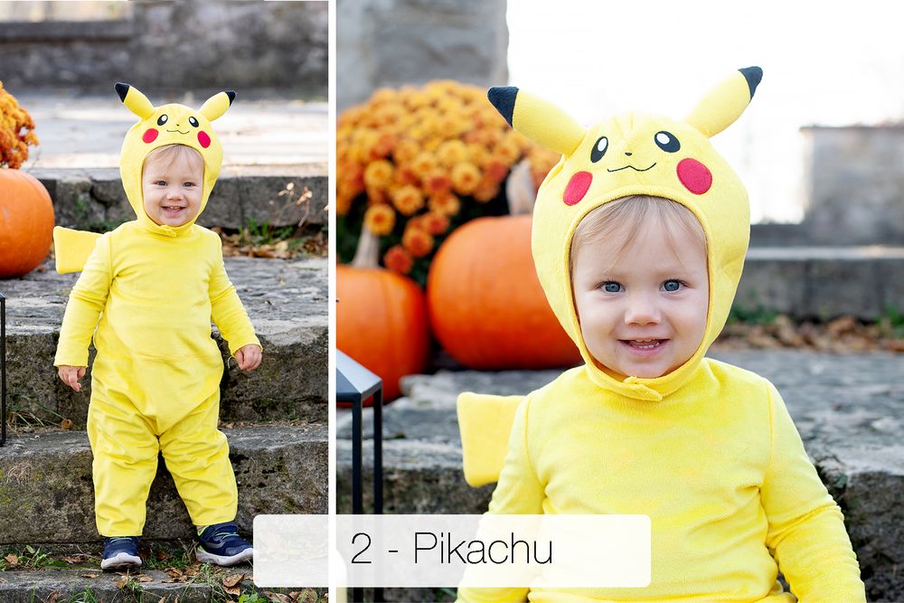 Toddler in a yellow Pikachu costume with ear hood and red cheeks stands on stone steps beside orange pumpkins and mums.
