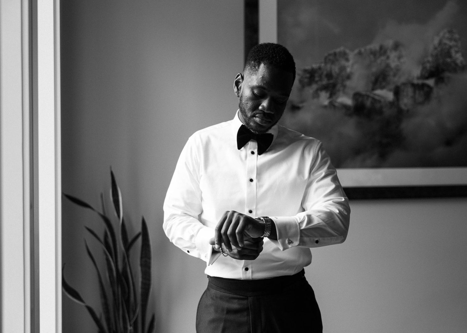 Groom fastening his cuffs in a white shirt and bow tie, Canmore wedding photographer