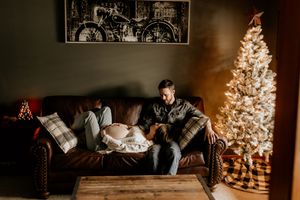 Cozy mom and dad during Lifestyle Maternity Photoshoot in Fort Wayne Indiana in home at Christmas time