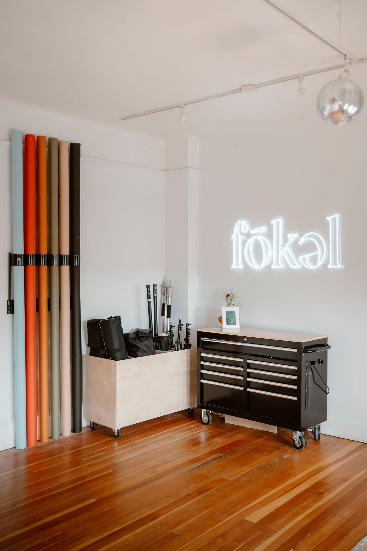 Modern studio space with illuminated 'fokal' sign and colored paper roll storage.