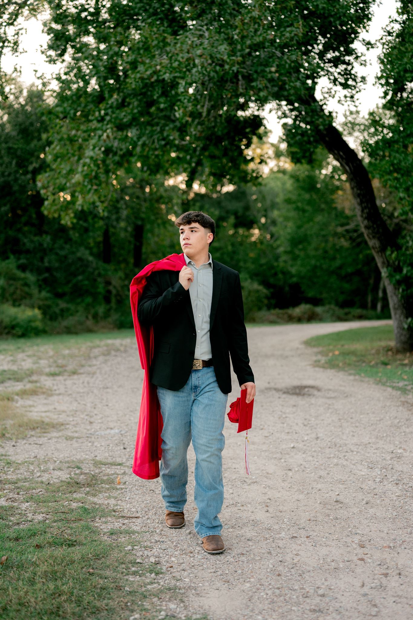 St. Thomas High School graduating senior walking with his red cap and gown.