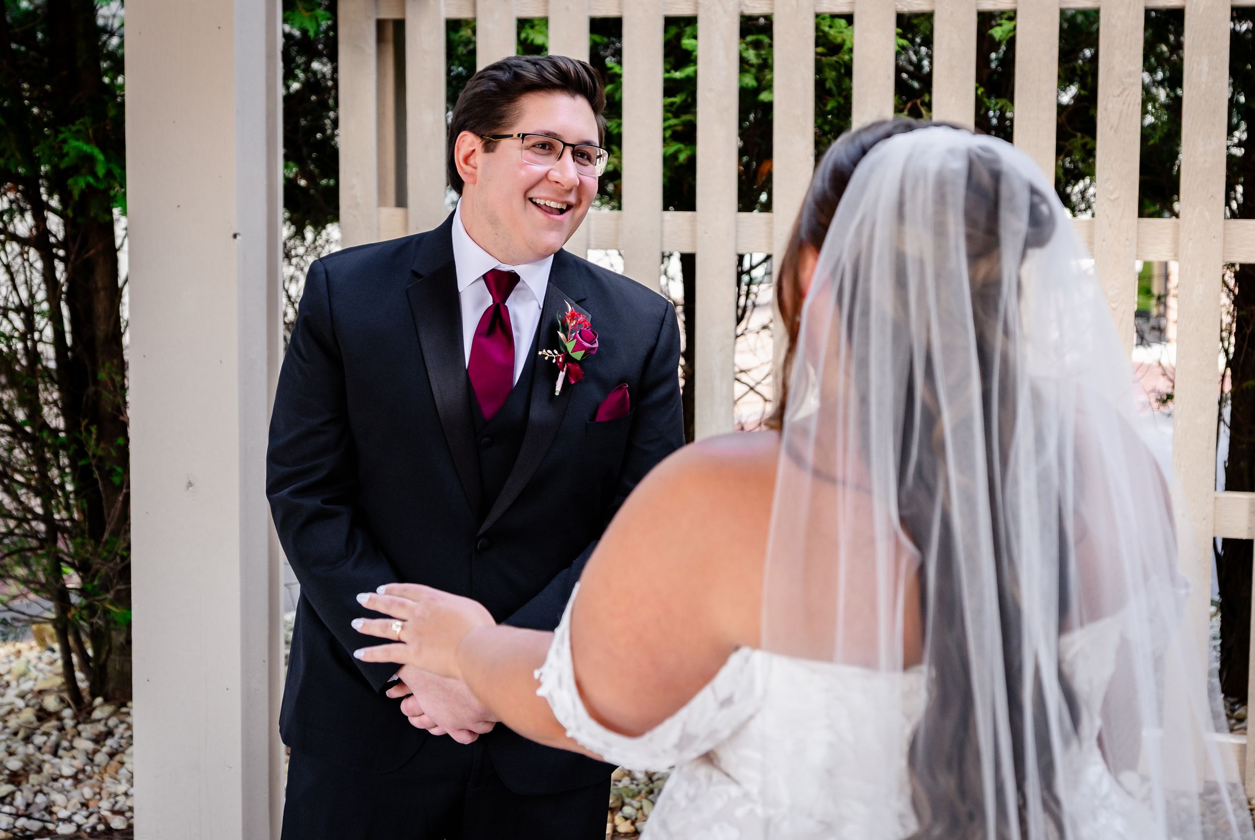 Groom smiling joyfully at his bride during an emotional first look moment at their wedding venue.
