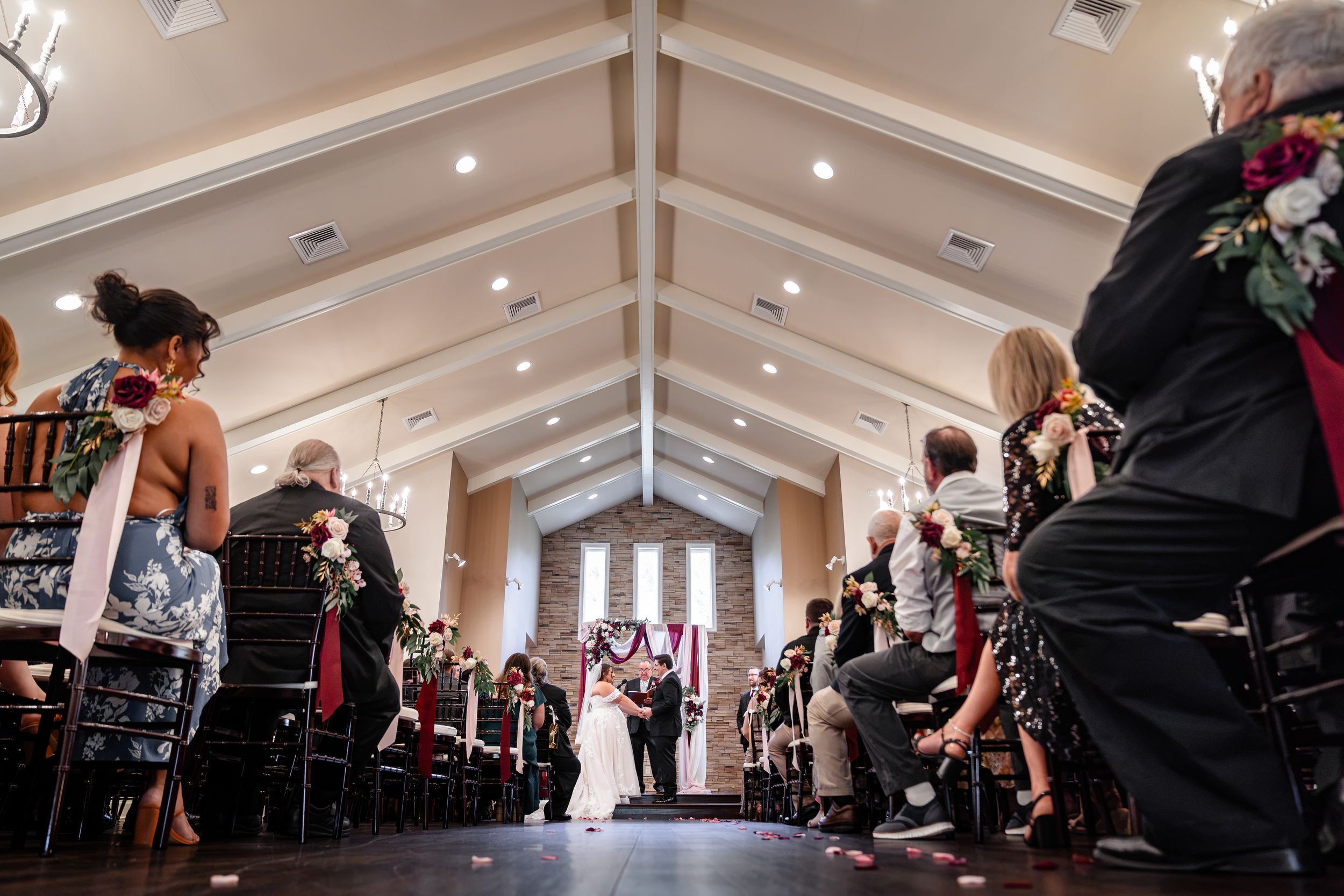 Wide-angle view of elegant chapel wedding ceremony with vaulted ceiling.