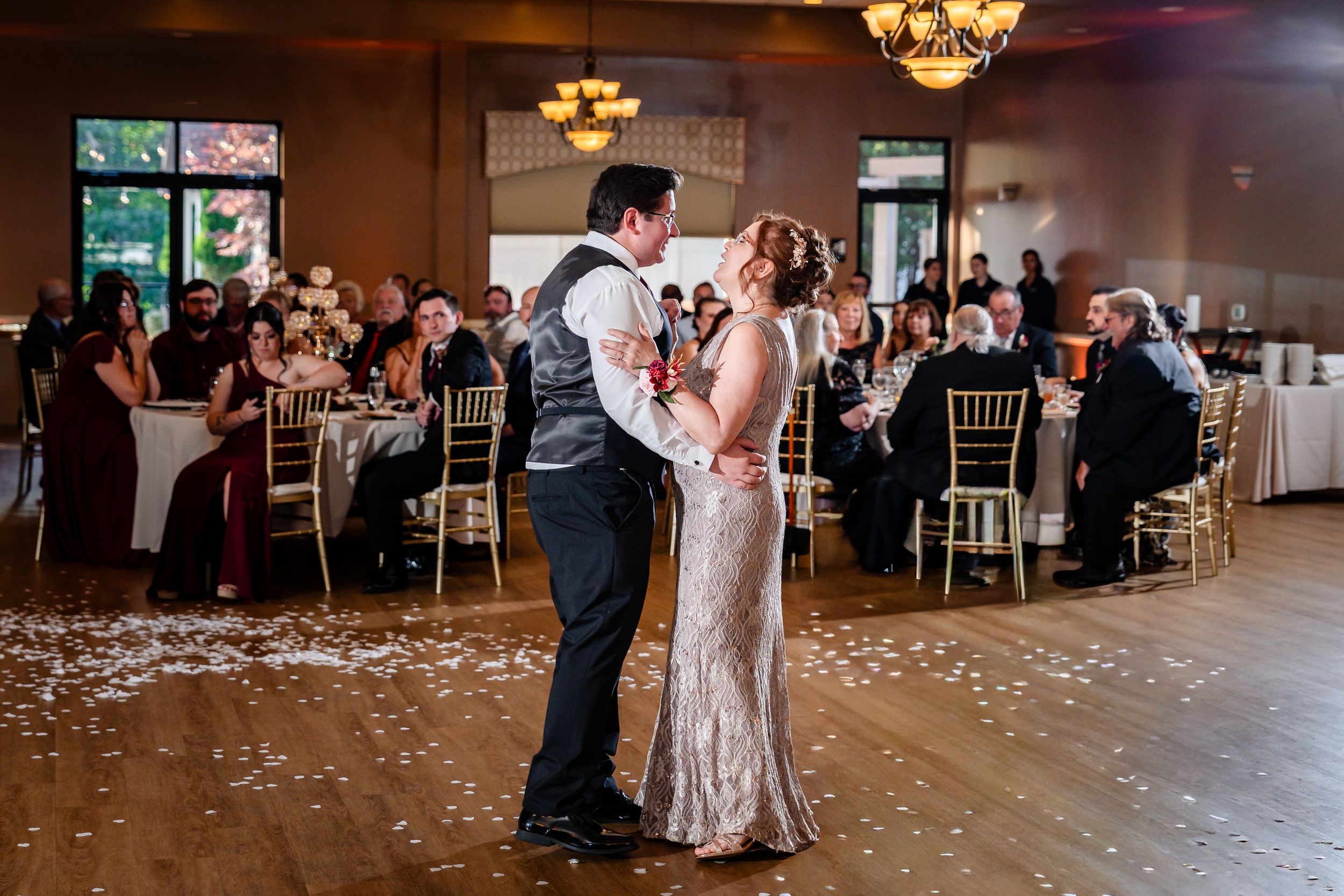 Bride and groom share romantic first dance on decorated ballroom floor at elegant wedding reception.