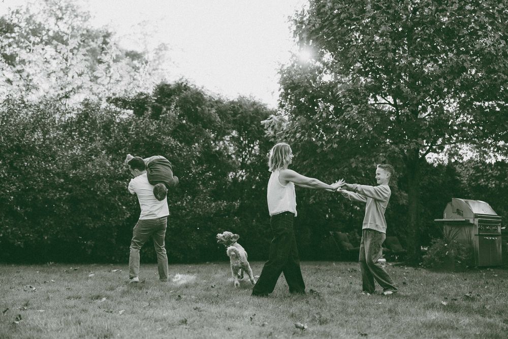 Children and a dog playing outdoors in a garden, captured in black and white photography.