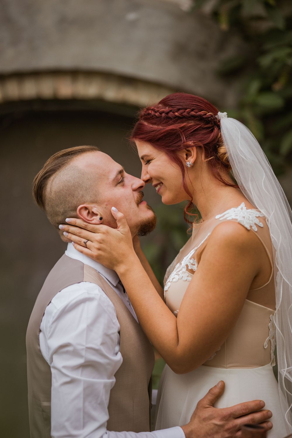 Romantikus esküvői jelenetsor, melyben ifjú pár osztozik meg egy meghitt pillanatban egy kültéri kerti környezetben.