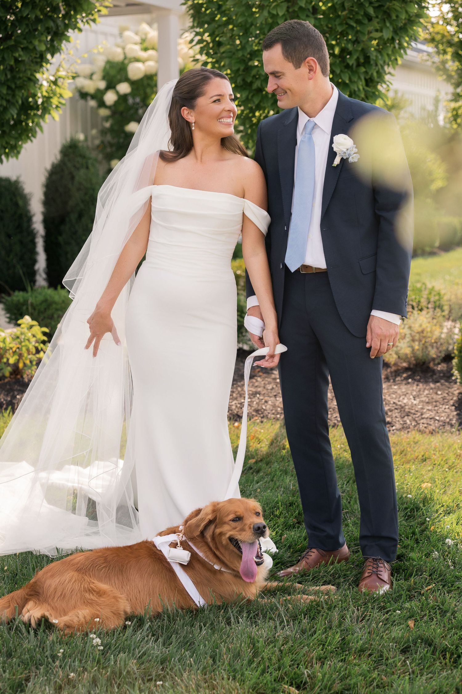 Bride and groom smiling together with their golden retriever dog wearing a bow tie on their wedding day in Ohio