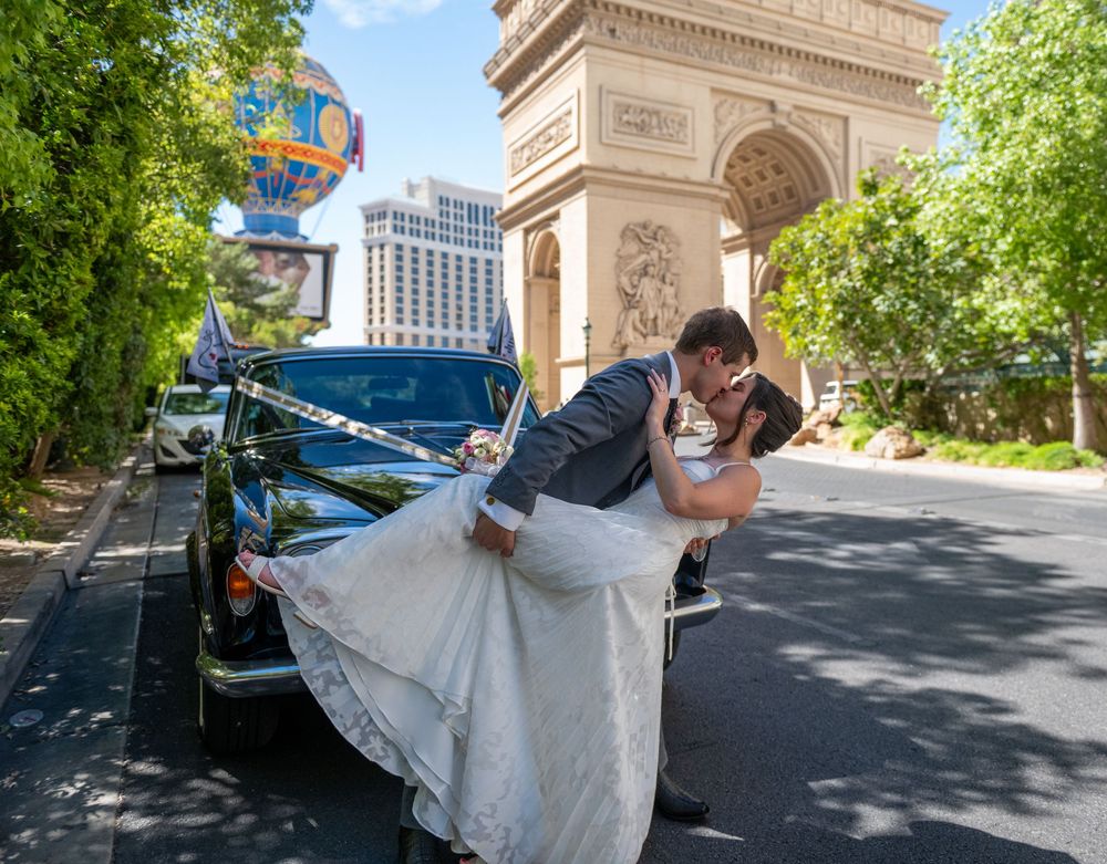 Groom dips bride in a romantic kiss near the Arc de Triomphe replica on the Las Vegas Strip.