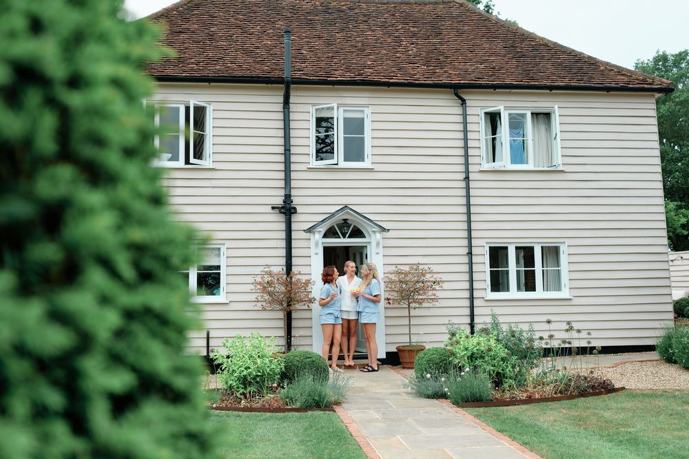 Family standing at the entrance of a white two-story house with a well-maintained garden and brick pathway.