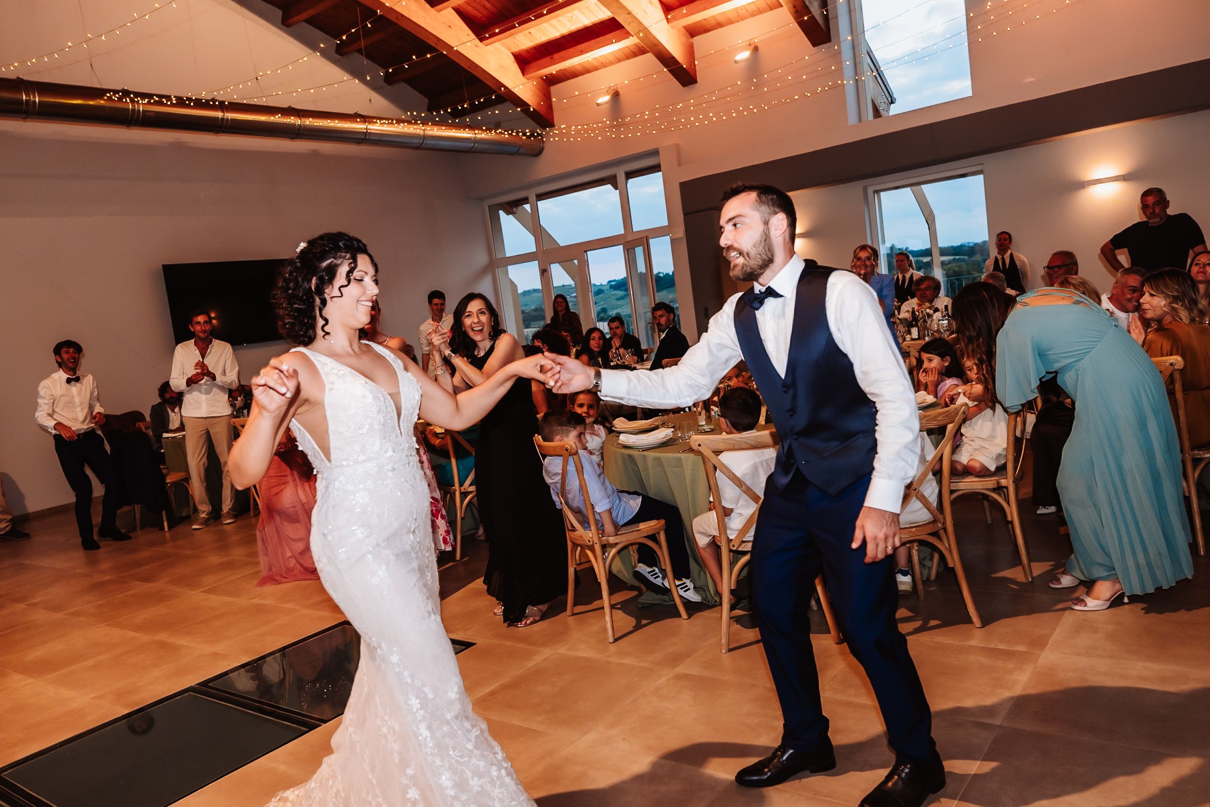Bride and groom share first dance at elegant wedding reception with guests watching.