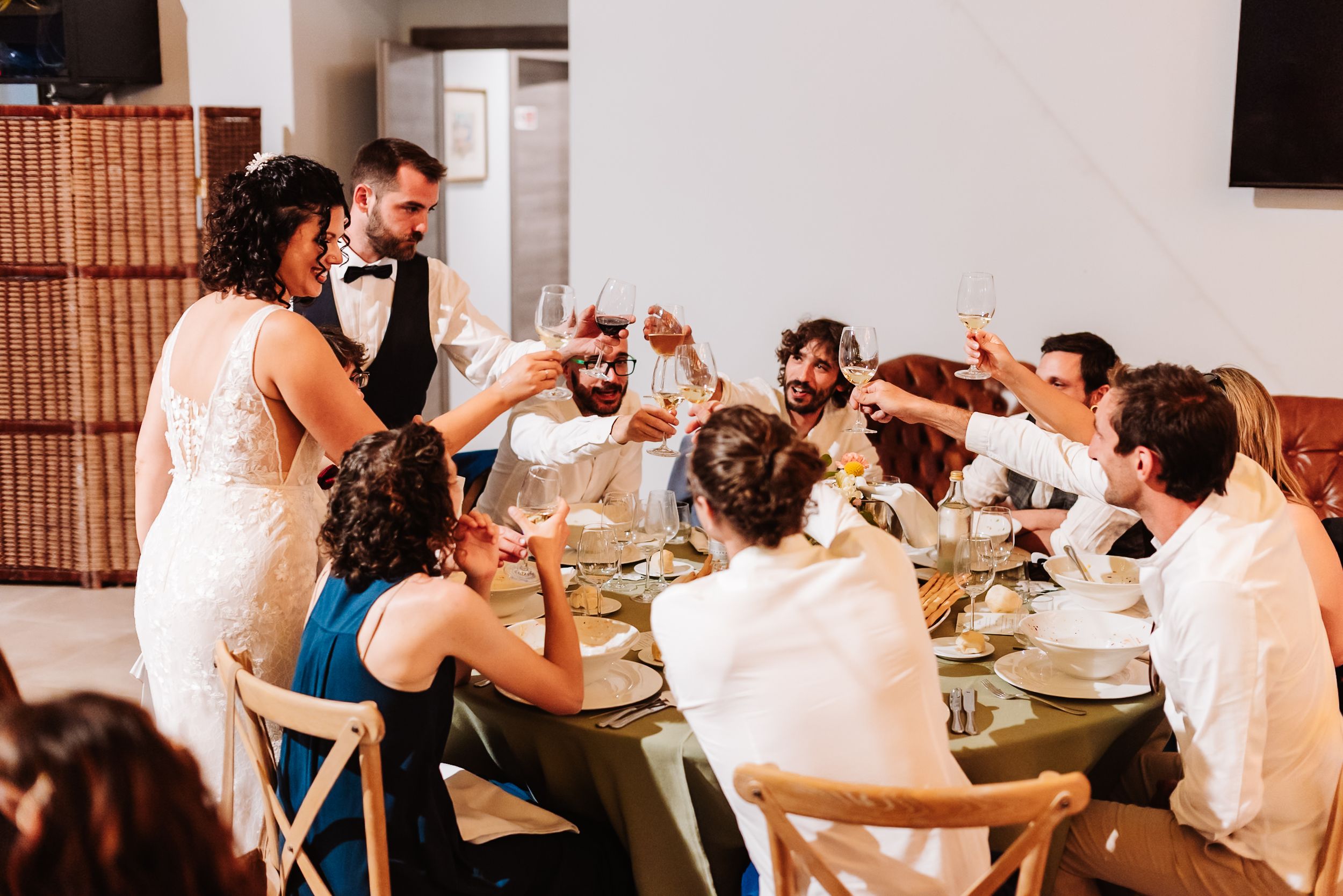 Wedding couple toasts with guests at decorated reception dinner table.
