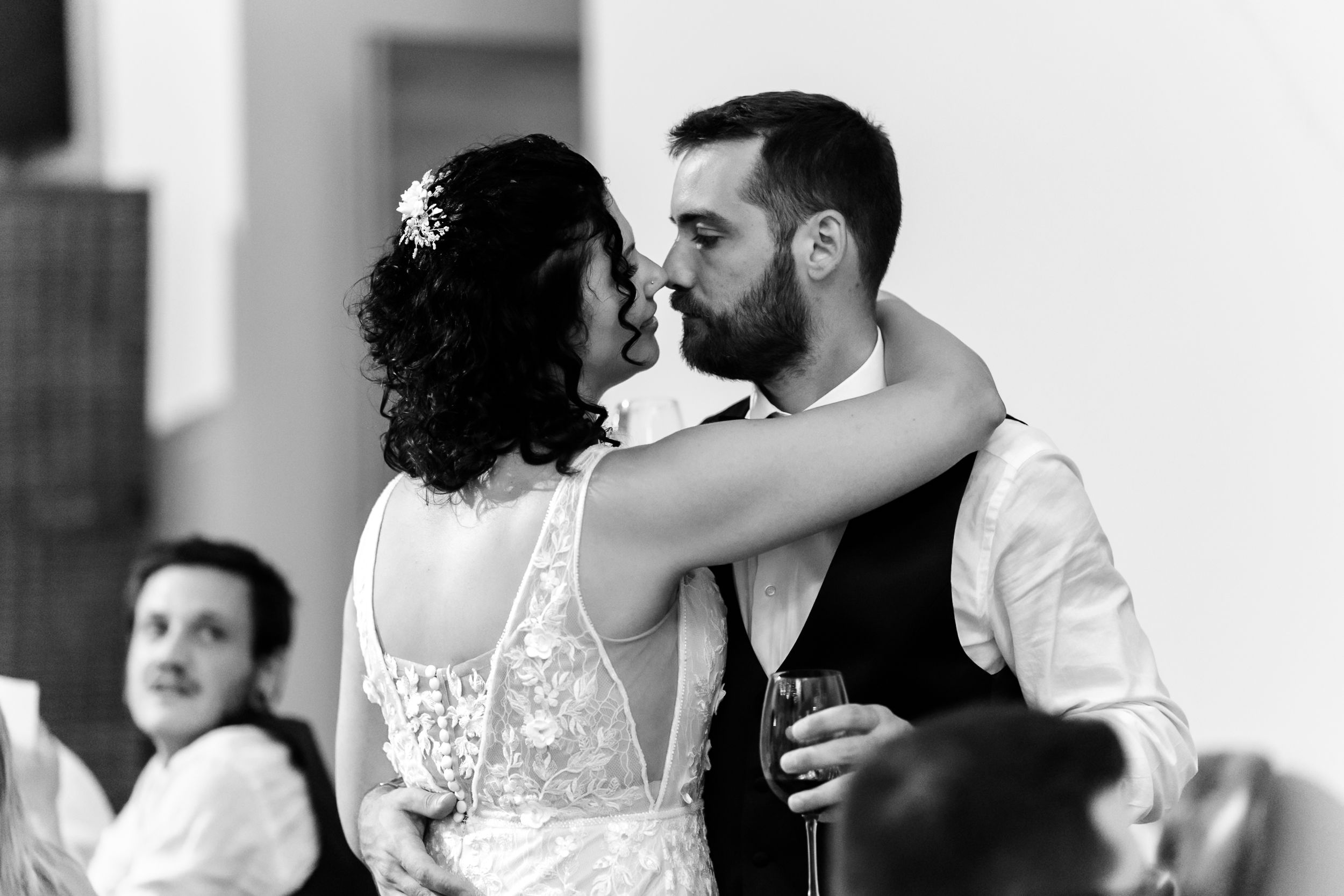 Black and white photo of a bride and groom sharing a kiss at their wedding reception.