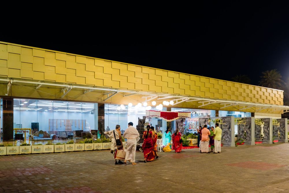 People in traditional attire gather outside a golden-facade building illuminated at night.