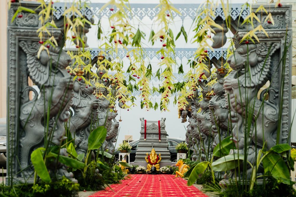 Ornate stone guardian statues flank red carpet entrance at decorated Hindu temple ceremony.