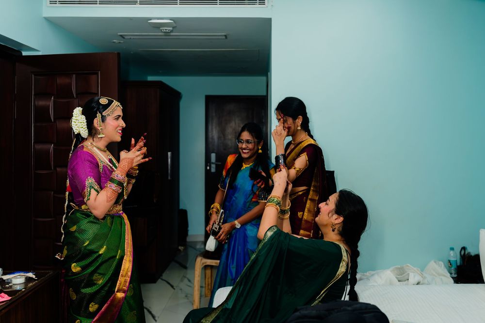 Indian women in vibrant sarees laughing together while getting ready for a traditional wedding celebration.