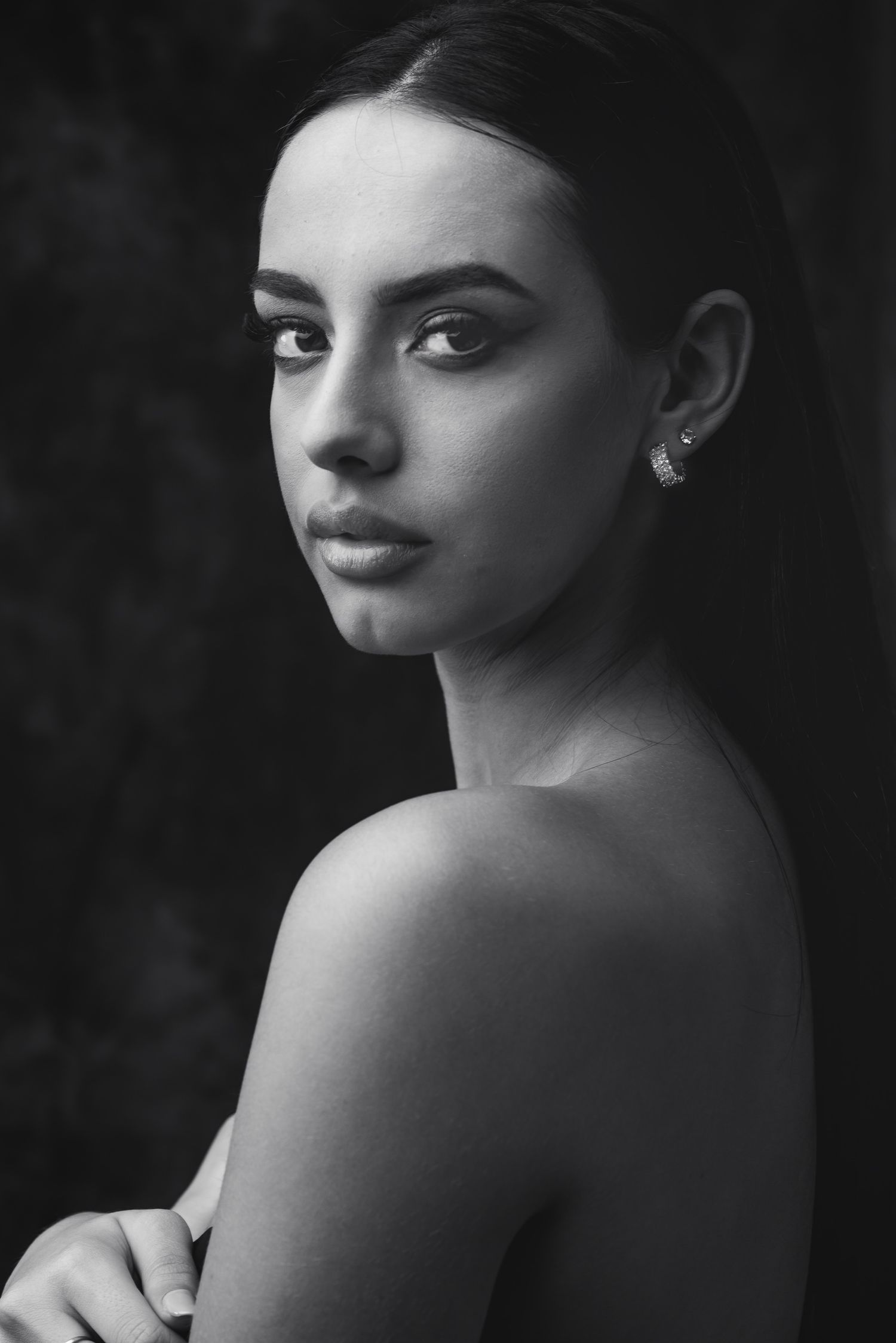 Ritratto di bellezza in bianco e nero con inquadratura stretta su una ragazza con spalle scoperte e sguardo profondo verso l'obiettivo
