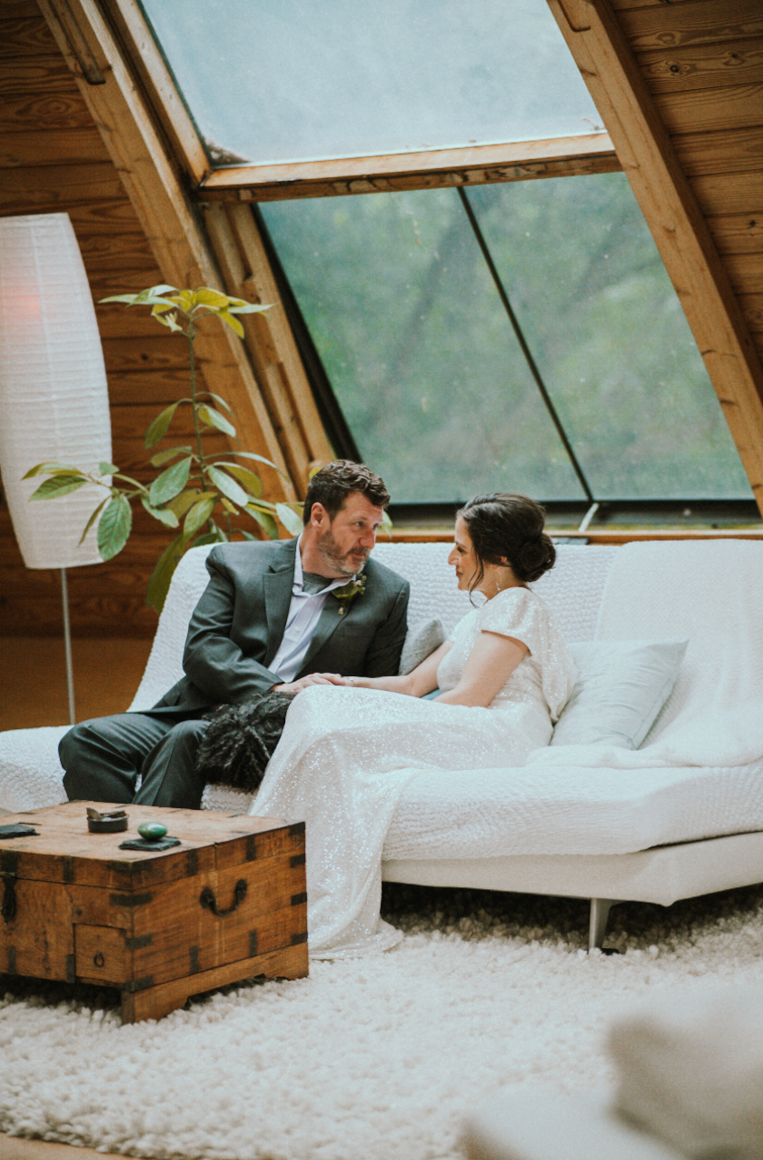 a couple talknig lovingly on the couch of their ARIBNB after their elopement
