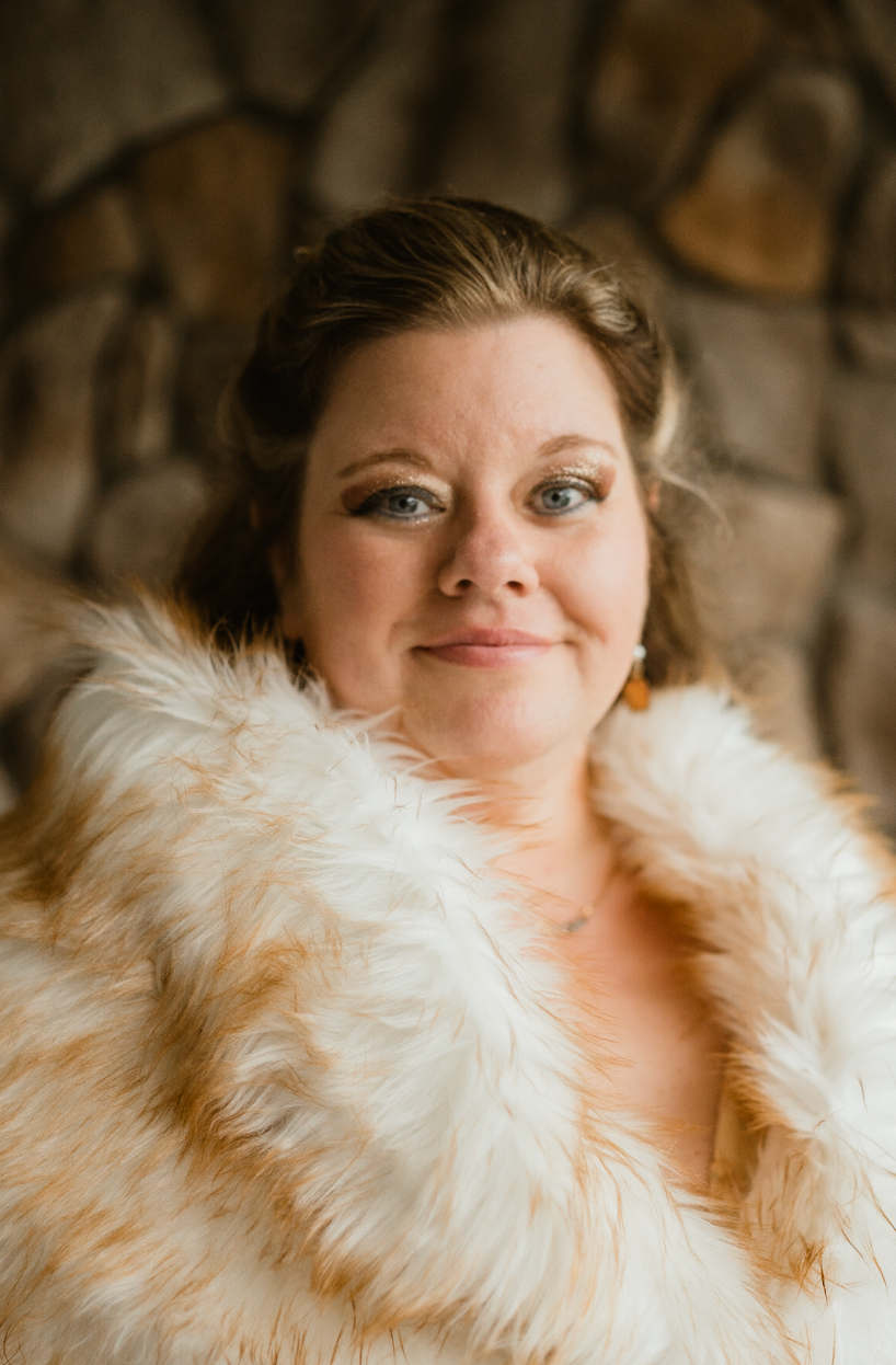 a bride looking happily at the camera in her fur coat and warm fall colors