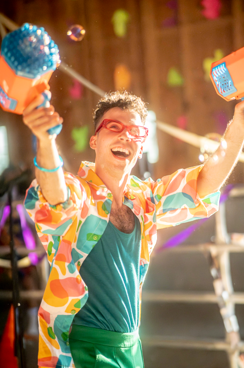 a fun photo of a man playing with giant bubble machines and smiling
