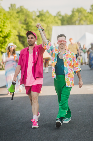 a young queer couple holding hands and celebrating after just getting married, both dawning colorful outfits