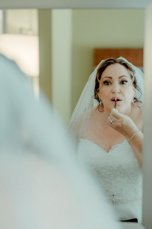 a bride doing her makeup in the mirror as she gets ready for her wedding day