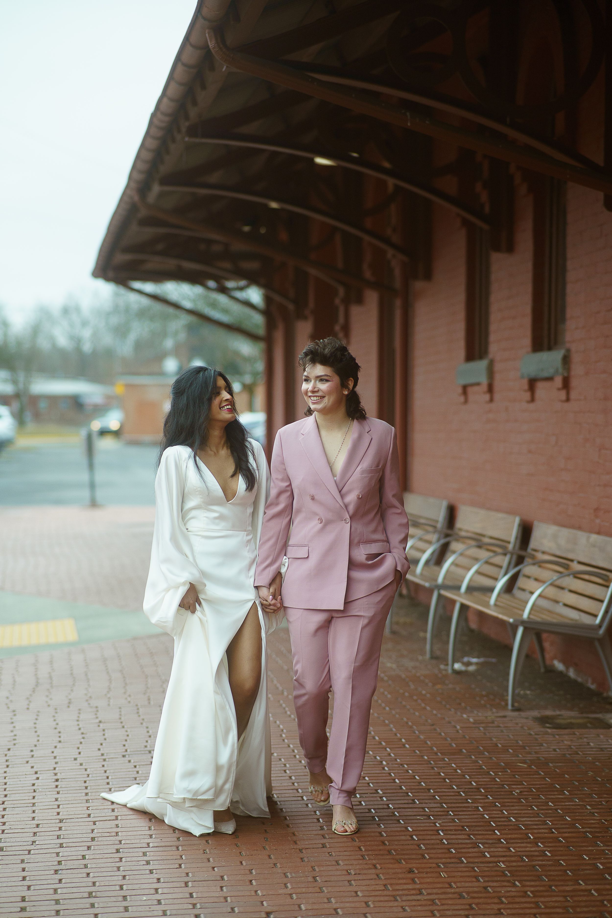 a young queer couple walking beside a train station