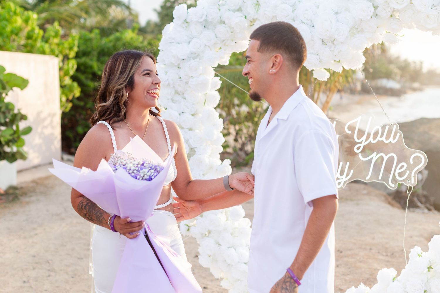 Marriage proposal. Man, woman, and decorative setup with white flower heart overlooking the ocean in Río Grande, Puerto Rico.