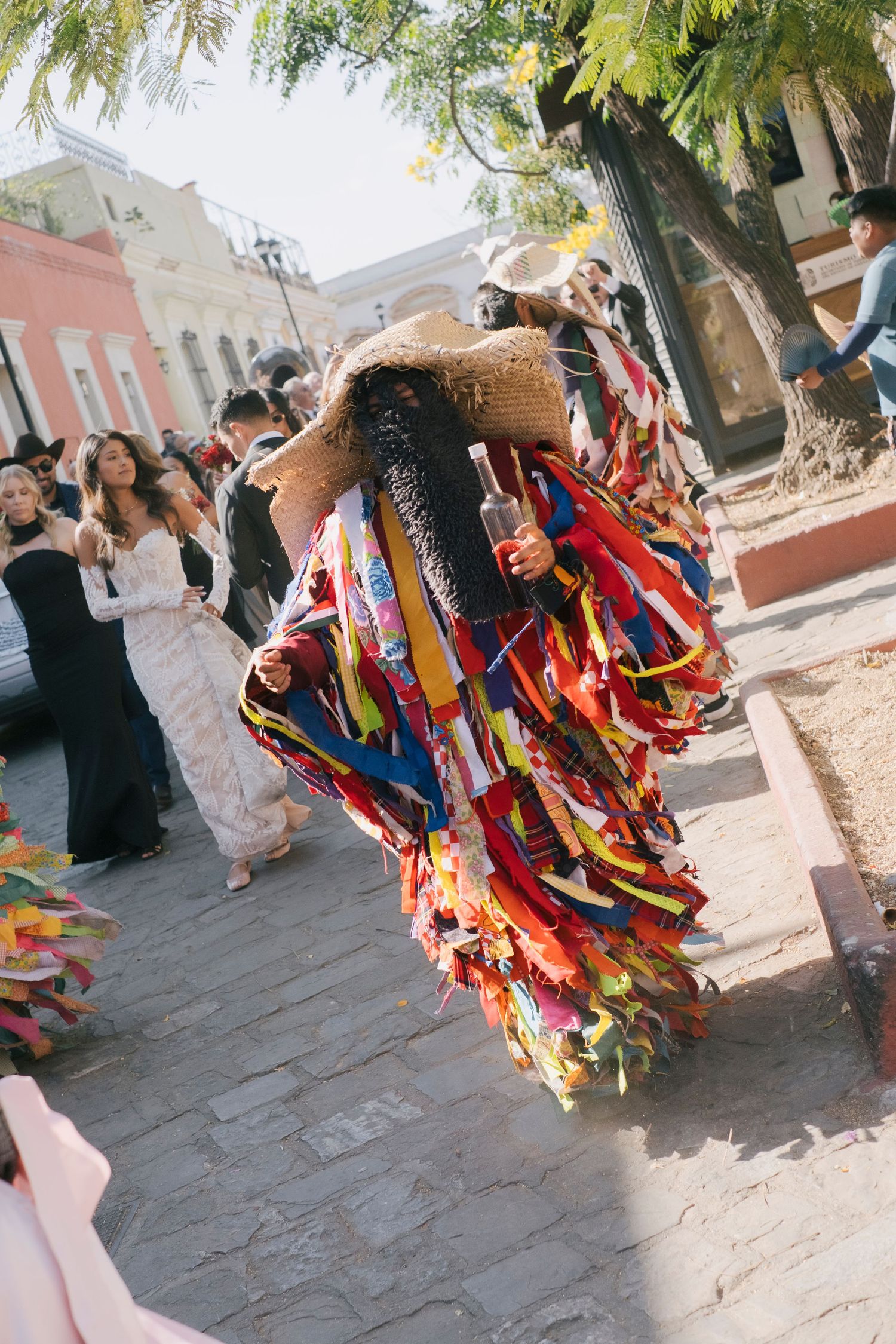 Colorful traditional Mexican dancer in vibrant ribbon costume performs at outdoor festival in Oaxaca plaza.