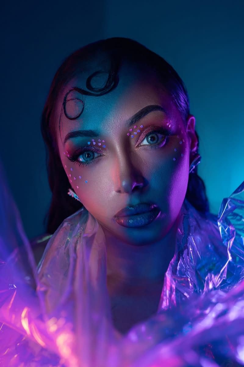 Neon editorial makeup portrait with dramatic lighting and creative beauty artistry.