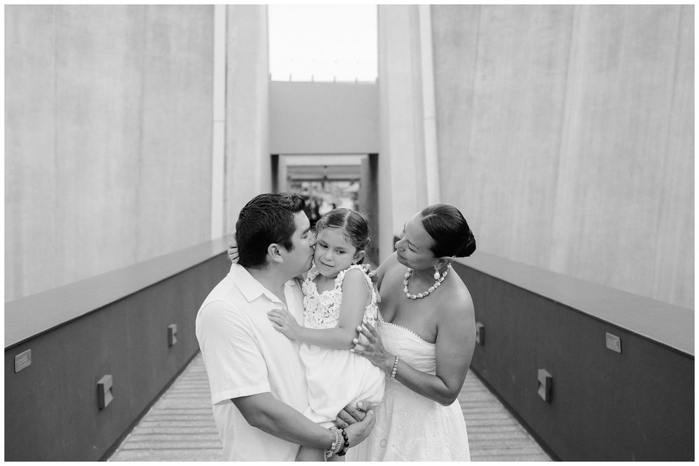 family sharing a tender moment during a family photo session at Dreams Bahia Mita, with parents kissing their daughter.