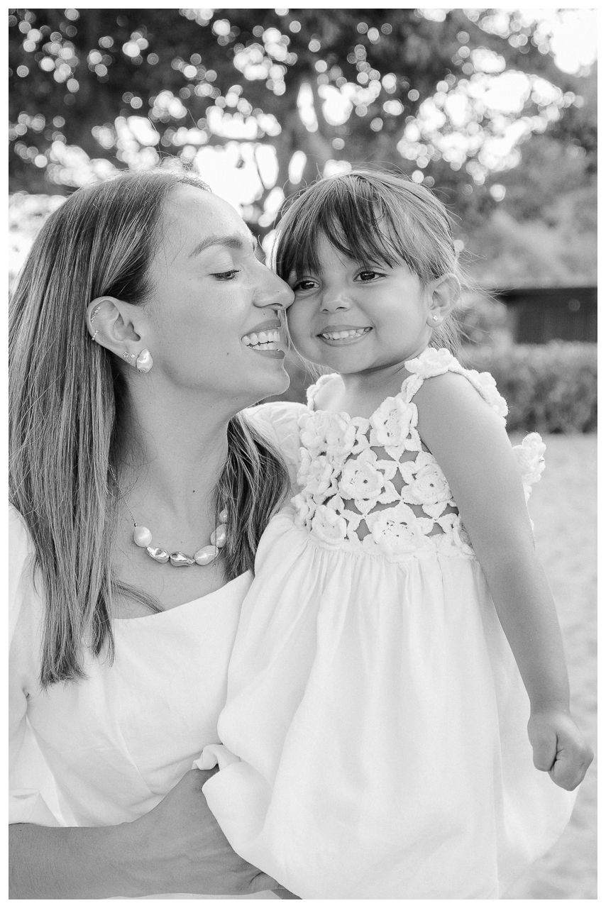 Mother and daughter sharing a sweet moment during a family photo session at Dreams Bahia Mita, with the young girl in a floral dress.