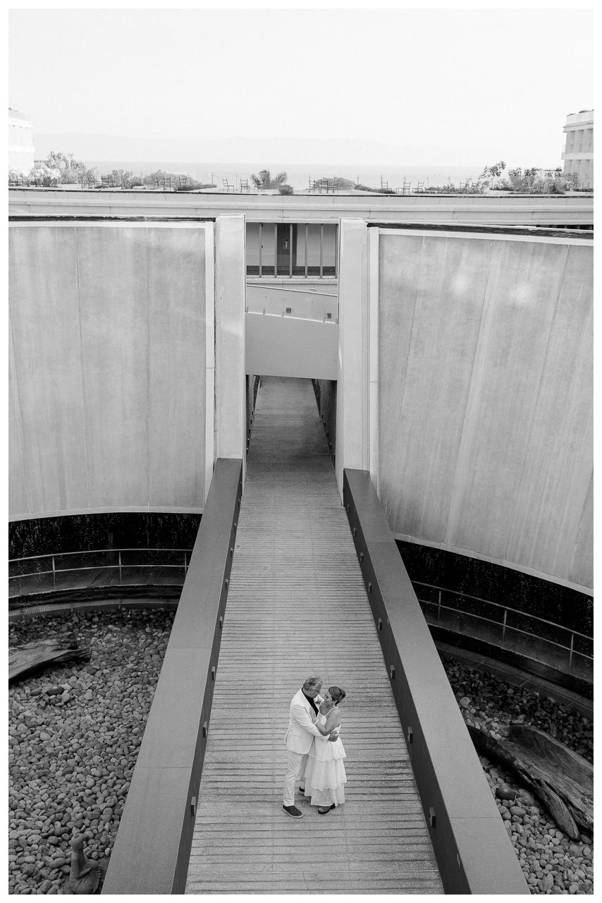 Anniversary couple photo session at Dreams Bahia Mita, with an intimate kiss framed by curved concrete walls.