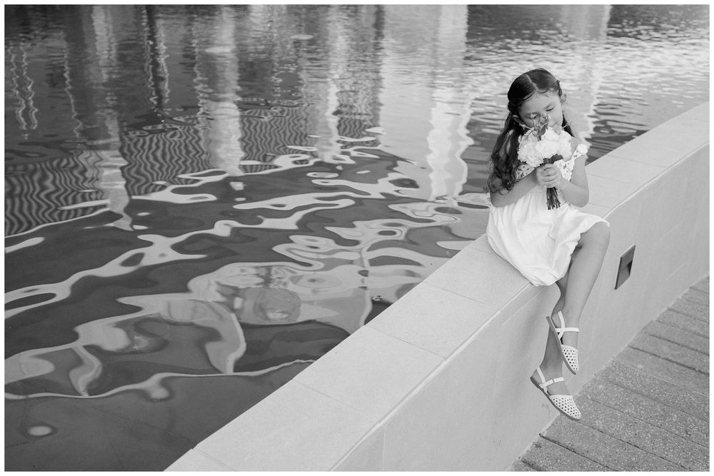 Granddaughter posing by a reflective pool during a family vacation in Dreams Bahia Mita, holding a bouquet during a photo session.
