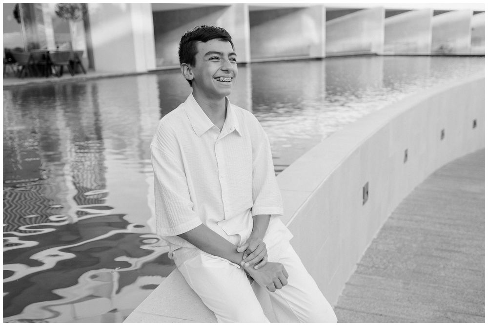 Grandson smiling by a reflective pool during a family vacation in Dreams Bahia Mita, part of a relaxed family photo session.