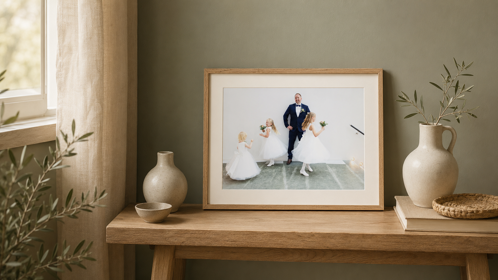 Framed wedding photo displayed on wooden bench with neutral decor, vases, and soft natural light in a cozy home setting.