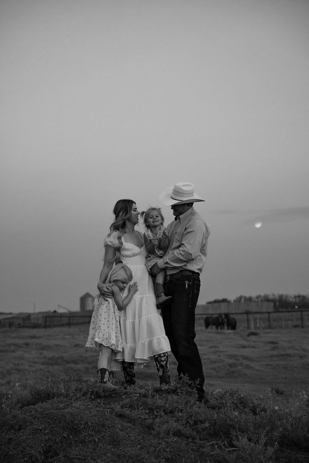 Black and white photo of a family with two children standing in a field at dusk during an Edmonton family photoshoot