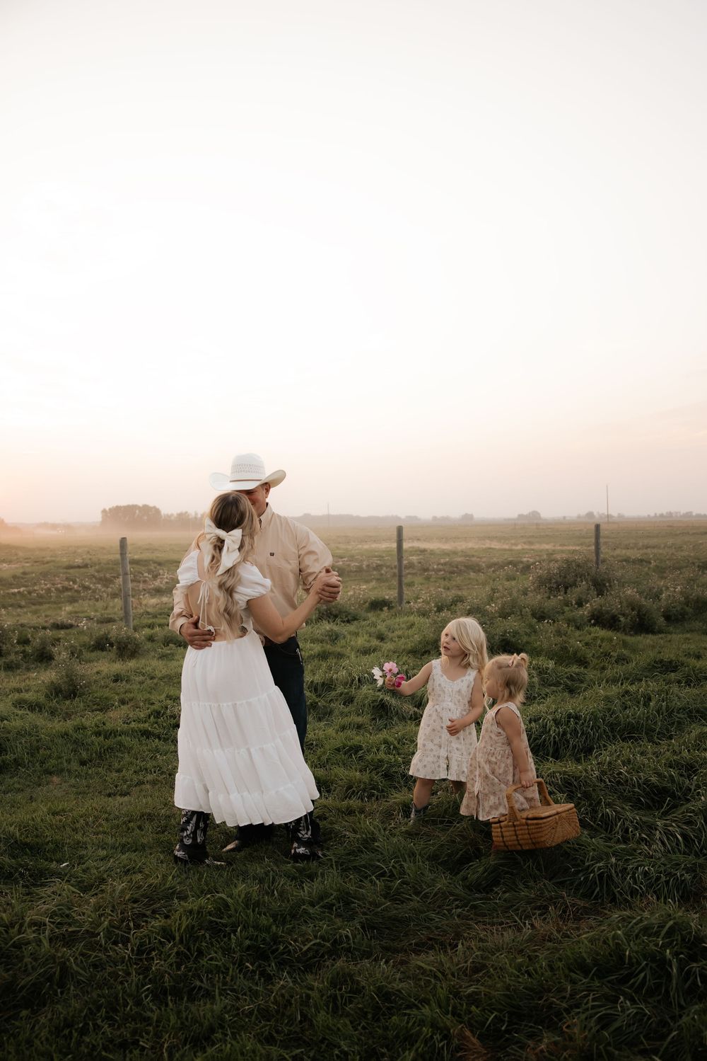 a mom and dad dance in a field as their young kids look on and admire their authentic love during thier family photoshoot in calgary