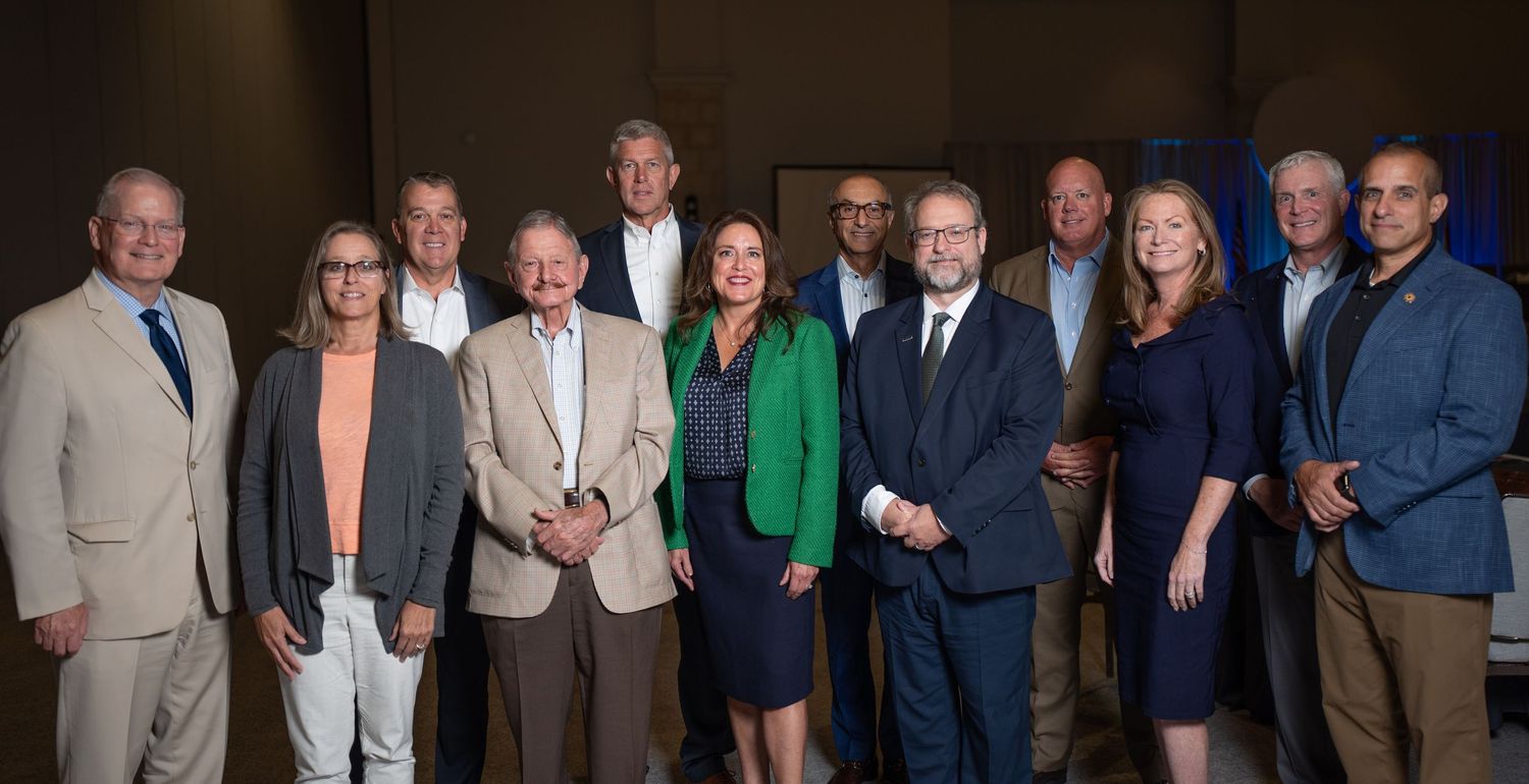 Group of professionals posing together for a formal photo at a business or corporate event.
