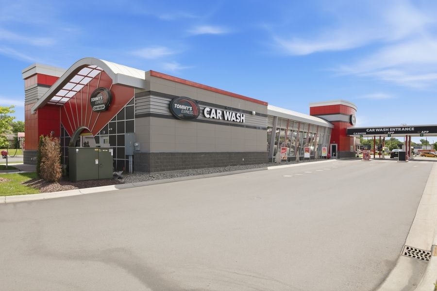 Exterior view of a modern car wash facility with red accents and signage on a sunny day.