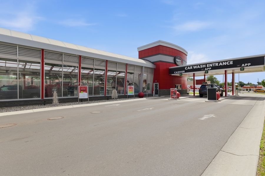 Tommy's Express Car Wash entrance with covered drive-through lanes and red accented modern building exterior.