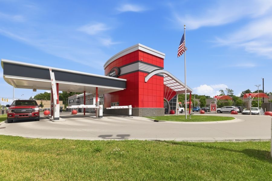 Tommy's Express car wash exterior featuring bold red building design with American flag and canopy.