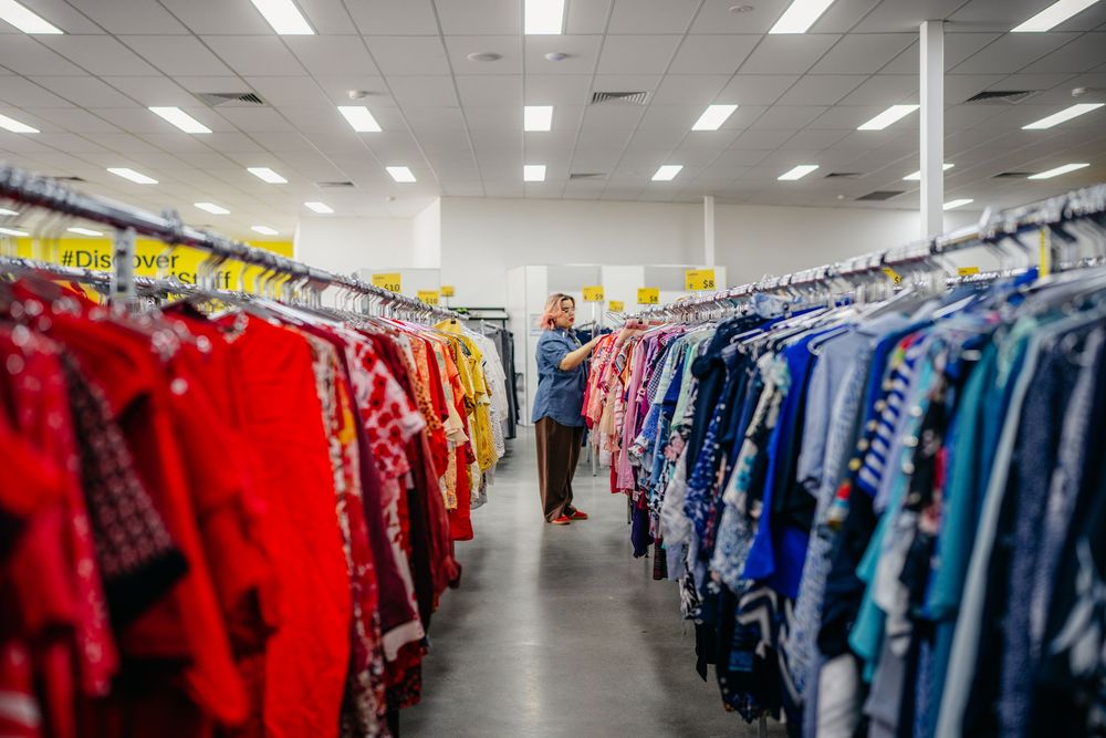 Colorful clothing racks filled with vibrant garments inside a large charity thrift store.